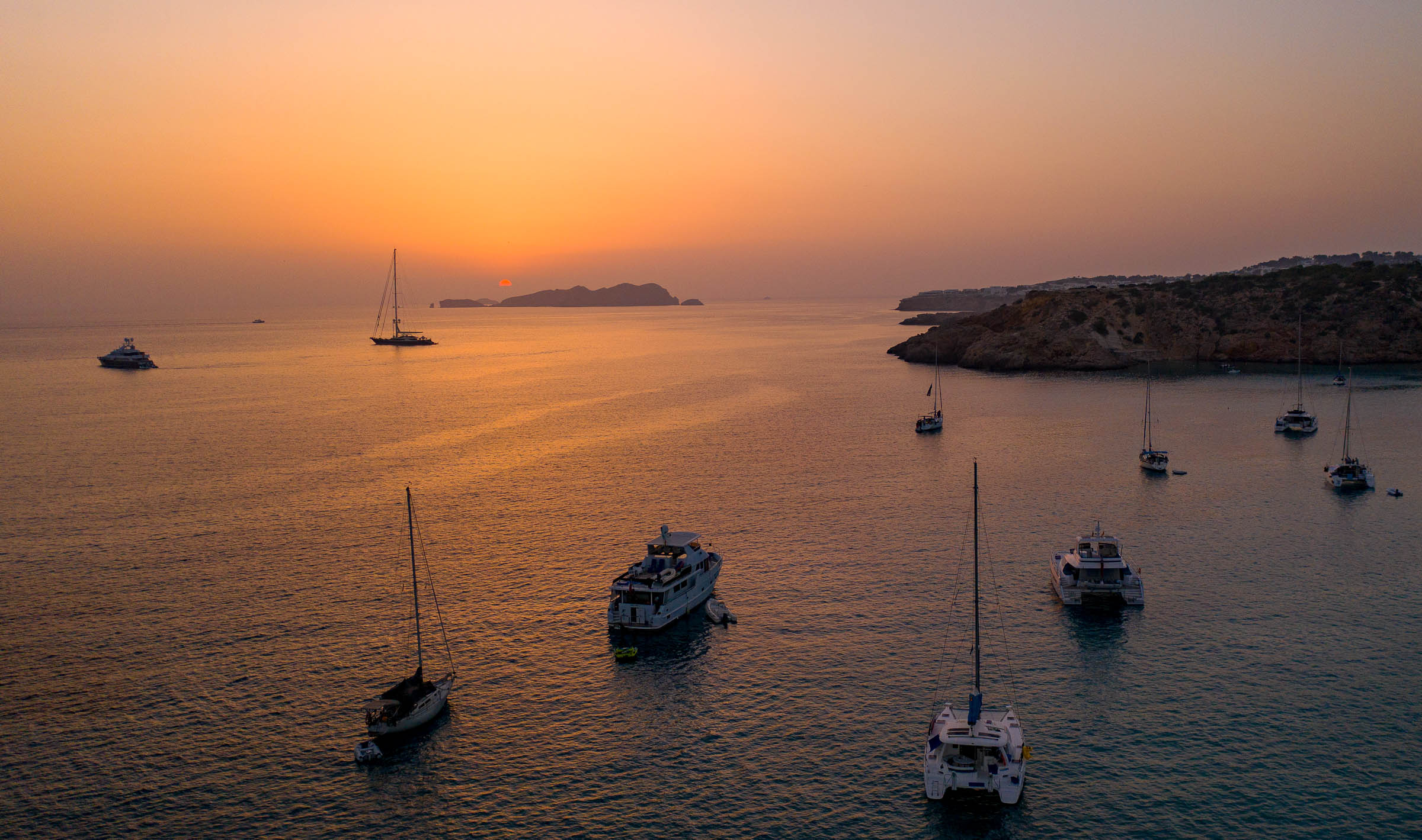 Sunset over harbor with boats and sailing vessels